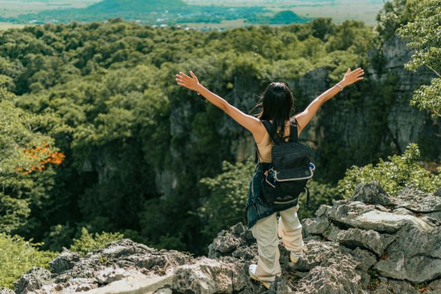 woman standing at the top of a canyon with arms spread apart